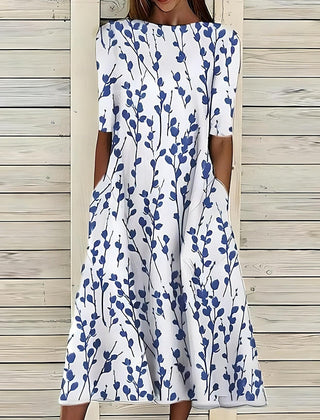 An Annie Coastal Bloom Dress by THE WHITMORE FAMILY featuring a blue floral pattern on lightweight fabric.