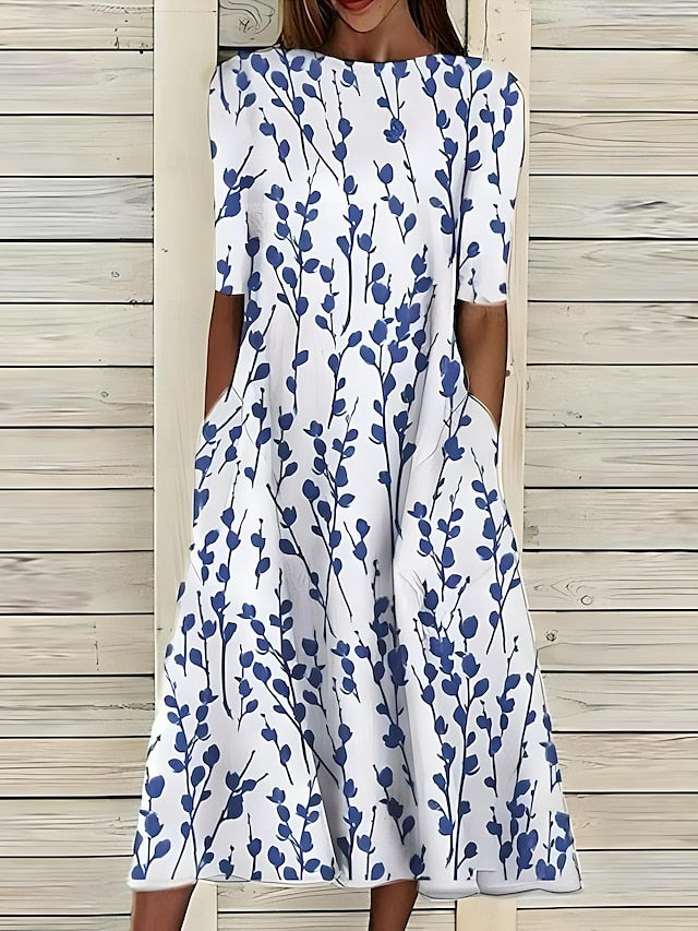 An Annie Coastal Bloom Dress by THE WHITMORE FAMILY featuring a blue floral pattern on lightweight fabric.