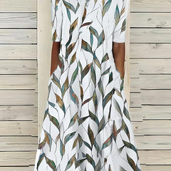 An Annie Coastal Bloom Dress by THE WHITMORE FAMILY, featuring a blue floral pattern, displayed flat on a white background.