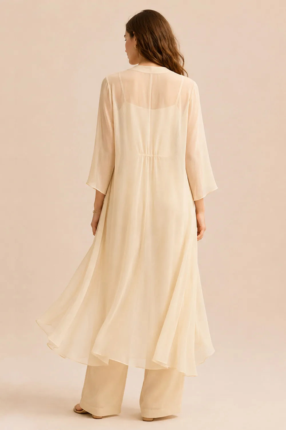 Elegant champagne dress featuring a refined camisole and chiffon jacket pant set by THE WHITMORE FAMILY, shown on a model.