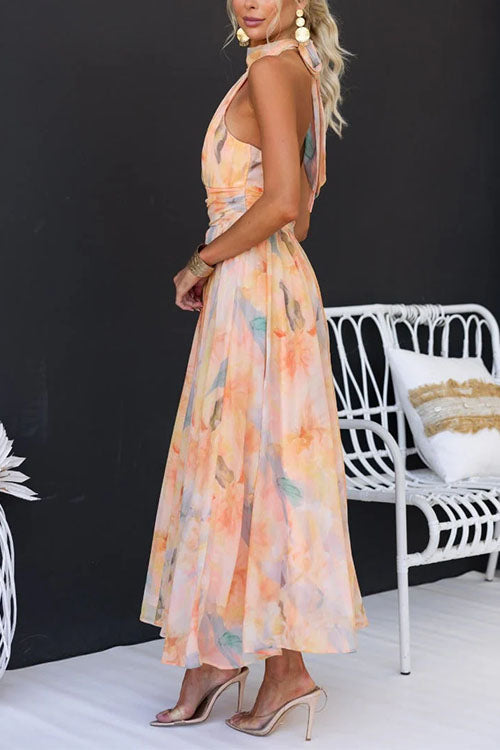 Peach halter maxi dress with colorful print by THE WHITMORE FAMILY, flowing and elegant for summer or special occasions.