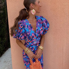 Purple Loren vibrant midi dress with puff sleeves, stylish for wedding guests, by THE WHITMORE FAMILY.