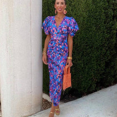Purple Loren vibrant midi dress with puff sleeves, perfect for wedding guest attire. Designed by THE WHITMORE FAMILY.