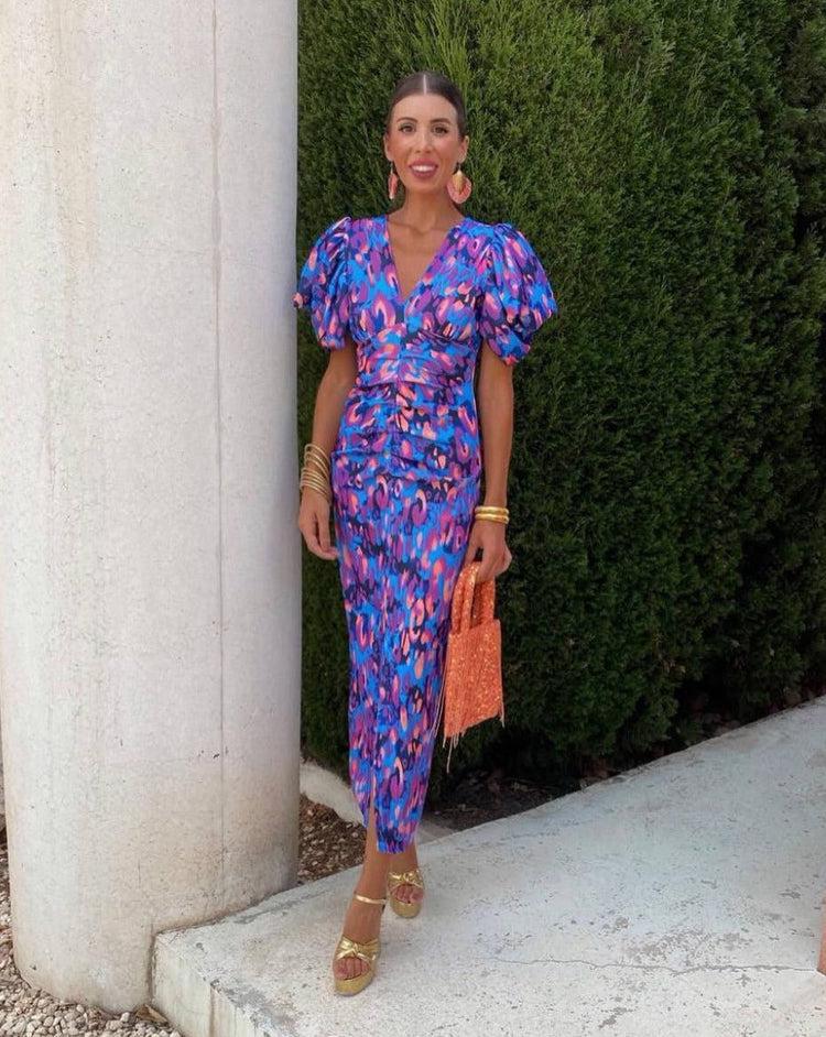 Purple Loren vibrant midi dress with puff sleeves, perfect for wedding guest attire. Designed by THE WHITMORE FAMILY.