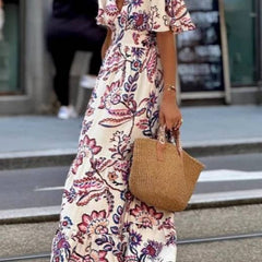 Purple floral print maxi dress with puff sleeves from THE WHITMORE FAMILY, featuring a flowing silhouette and elegant design.