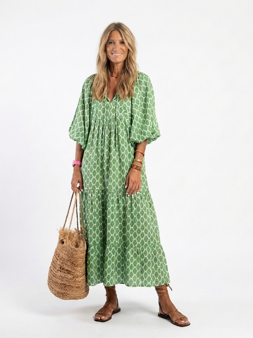 A woman wearing the Apolline three-quarter sleeve V-neck patterned midi dress by THE WHITMORE FAMILY, showcasing its stylish design.