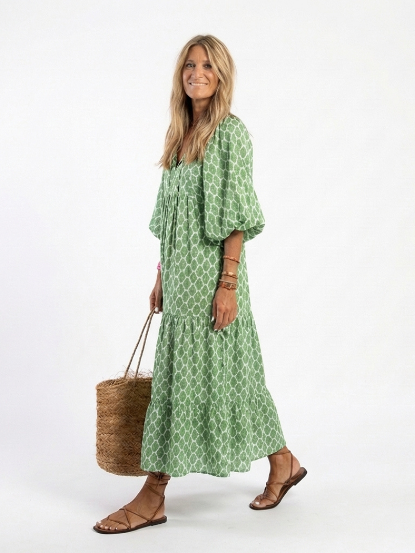 A woman wearing the Apolline three-quarter sleeve V-neck patterned midi dress by THE WHITMORE FAMILY, standing outdoors.
