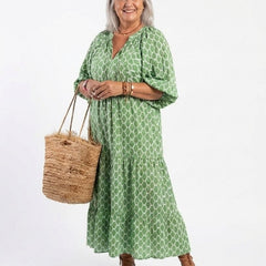 A model wearing the Apolline three-quarter sleeve V-neck patterned midi dress by THE WHITMORE FAMILY, showcasing its stylish design.