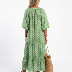 A model wearing the Apolline three-quarter sleeve v-neck patterned midi dress by THE WHITMORE FAMILY, featuring a stylish and elegant design.