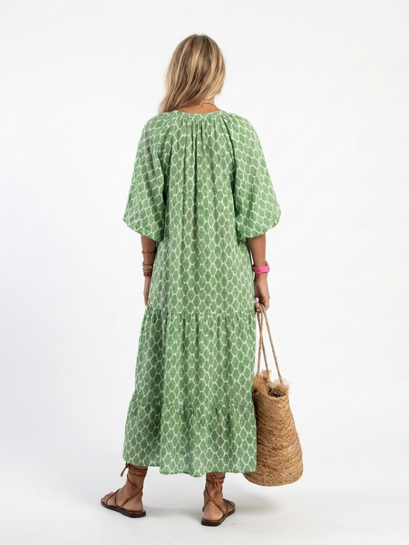 A model wearing the Apolline three-quarter sleeve v-neck patterned midi dress by THE WHITMORE FAMILY, featuring a stylish and elegant design.