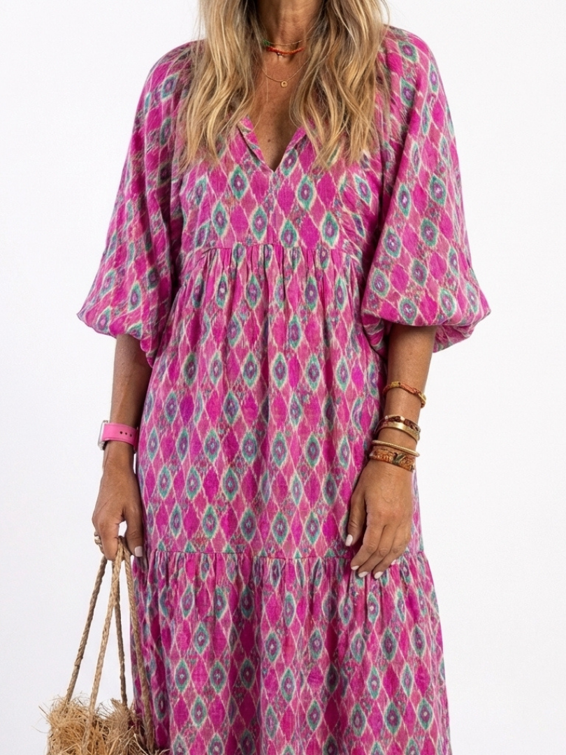 A model wearing the Apolline three-quarter sleeve V-neck patterned midi dress by THE WHITMORE FAMILY, showcasing its stylish design.