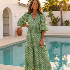 A woman wearing the Apolline midi dress by THE WHITMORE FAMILY, featuring three-quarter sleeves, V-neck, and a patterned design.