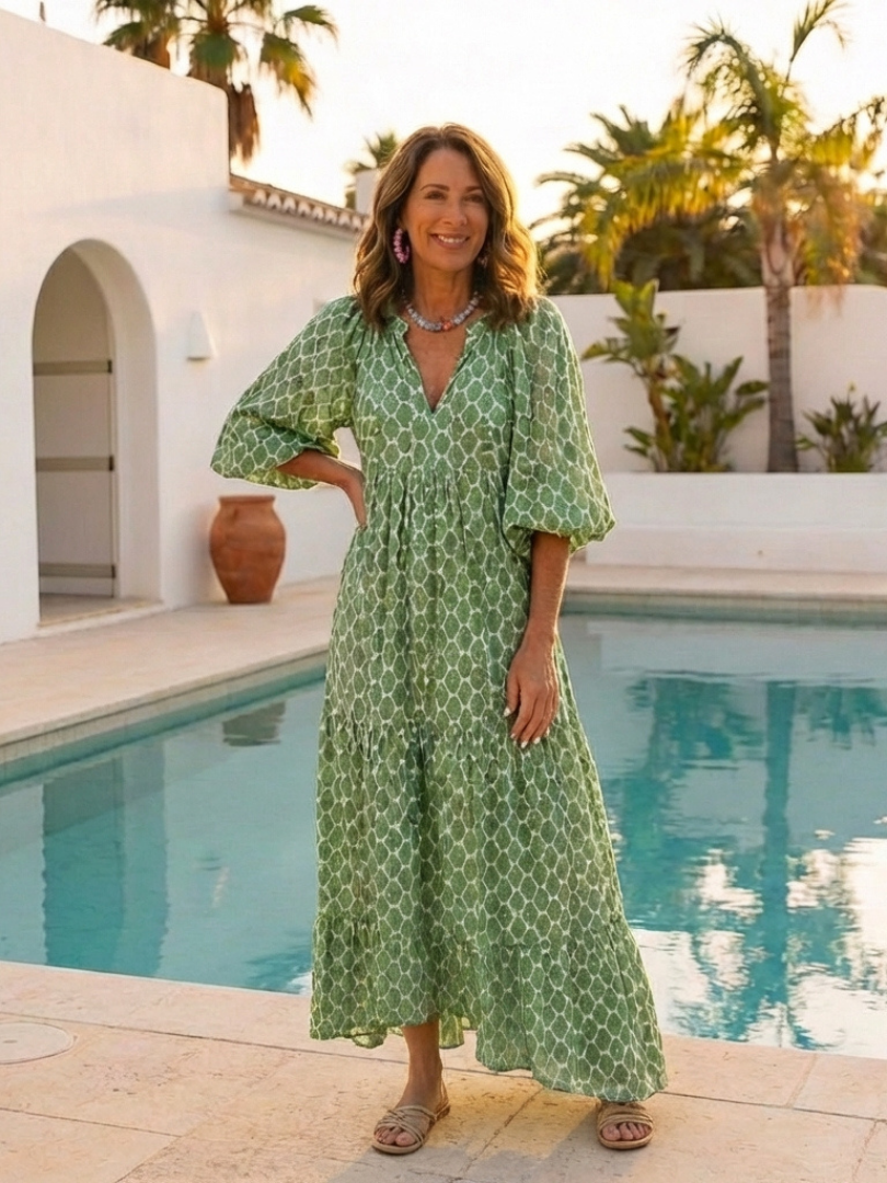 A woman wearing the Apolline midi dress by THE WHITMORE FAMILY, featuring three-quarter sleeves, V-neck, and a patterned design.
