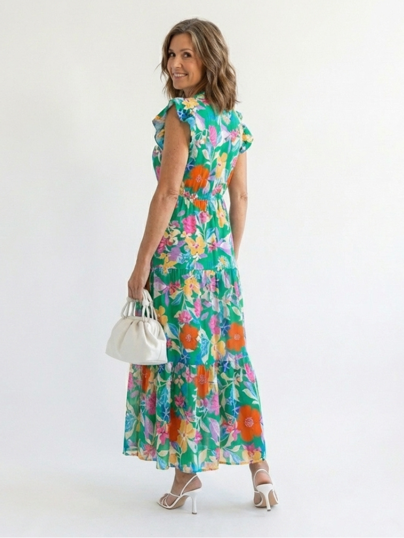 Lila floral V-neck tiered midi dress by THE WHITMORE FAMILY, showing the flowing fabric and vibrant floral pattern.