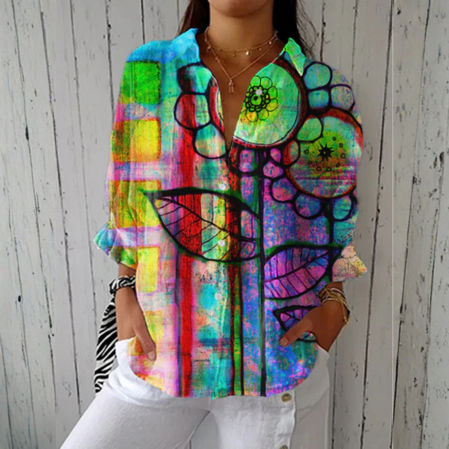 Multicolor Bianca™ Artistic Bloom Blouse by THE WHITMORE FAMILY displayed on a hanger with floral pattern and lightweight fabric.