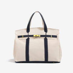 The Camille Boat Tote by THE WHITMORE FAMILY, a stylish canvas tote with leather handles and spacious interior, displayed on a white background.