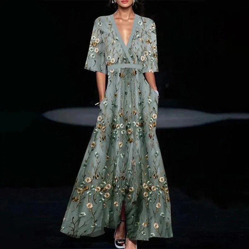 Hazel floral maxi dress by THE WHITMORE FAMILY featuring a belted waist and V-neck, displayed on a hanger against a plain background.