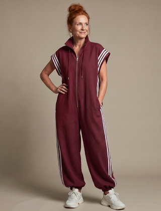 Red Lark Zip Front Stripe Panel Jumpsuit by THE WHITMORE FAMILY, featuring a front zipper and bold stripe details.