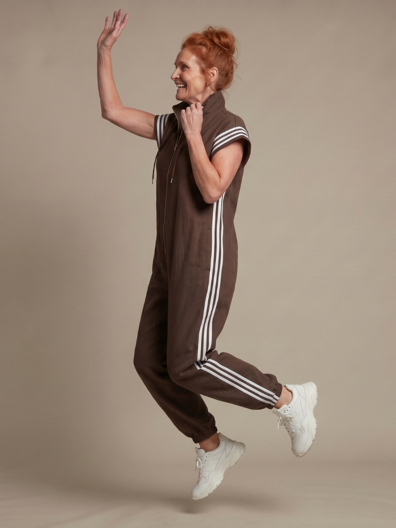 Red Lark zip front stripe panel jumpsuit by THE WHITMORE FAMILY, featuring a fitted silhouette and bold stripe details.