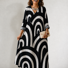 Cynthia Summer Breeze Printed Dress by THE WHITMORE FAMILY displayed on a hanger with floral and colorful patterns.
