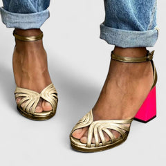 Gold Noelyrah sophisticated sandal heels by THE WHITMORE FAMILY, shown from side view with elegant strap details.