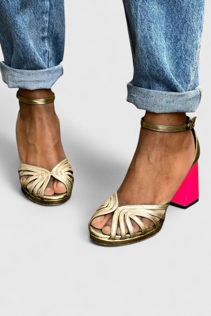 Gold Noelyrah sophisticated sandal heels by THE WHITMORE FAMILY, shown from side view with elegant strap details.