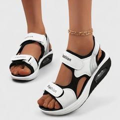 White and black Rhea Cushy Sandals by THE WHITMORE FAMILY featuring soft straps and cushioned soles for comfortable wear.