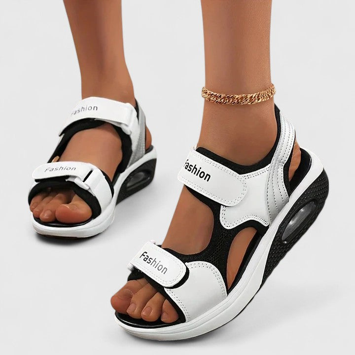 White and black Rhea Cushy Sandals by THE WHITMORE FAMILY featuring soft straps and cushioned soles for comfortable wear.
