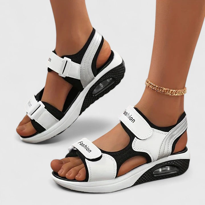 White and black Rhea™ Cushy Sandals by THE WHITMORE FAMILY featuring comfortable straps and cushioned soles.