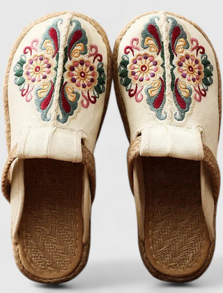 White handmade floral mules by THE WHITMORE FAMILY, featuring a comfortable slip-on design with floral embellishments.