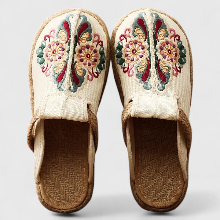 White handmade floral mules by THE WHITMORE FAMILY, featuring a comfortable slip-on design with floral embellishments.