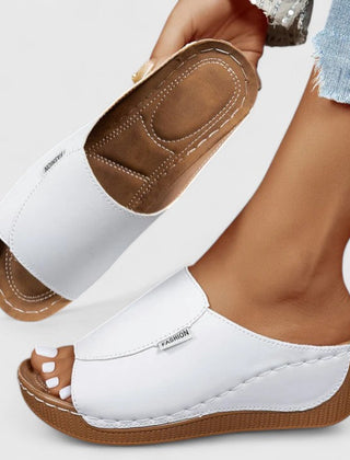 White Celestria™ orthopedic sandals by THE WHITMORE FAMILY with cushioned straps and supportive soles for comfort.
