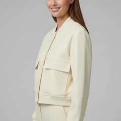 Women’s beige bomber jacket with baseball collar and snap buttons, designed by THE WHITMORE FAMILY, featuring a stylish casual look.
