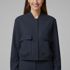Beige women’s bomber jacket with baseball collar and snap buttons, by THE WHITMORE FAMILY, displayed on a hanger.