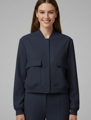 Beige women’s bomber jacket with baseball collar and snap buttons, by THE WHITMORE FAMILY, displayed on a hanger.