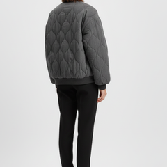 Women’s grey bomber jacket by THE WHITMORE FAMILY with snap closure and quilted surface, styled for a modern look.
