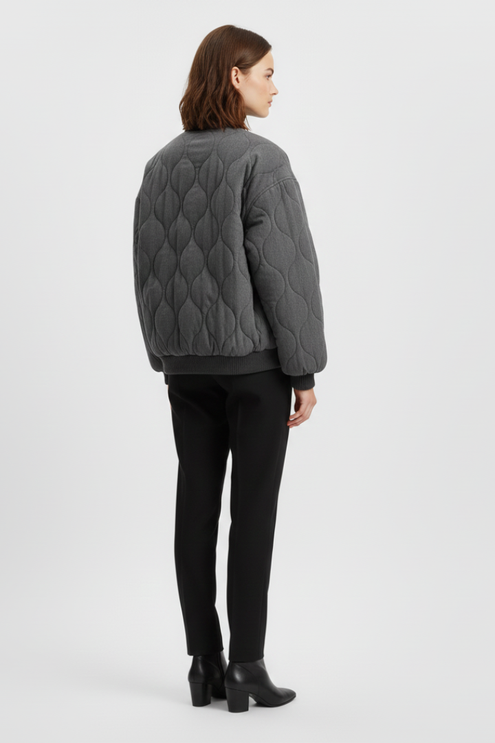 Women’s grey bomber jacket by THE WHITMORE FAMILY with snap closure and quilted surface, styled for a modern look.