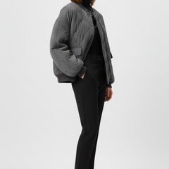 Women's grey bomber jacket by THE WHITMORE FAMILY with snap closure and quilted surface, shown on a model.