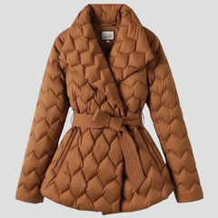 Women’s down coat by THE WHITMORE FAMILY in caramel with belted waist and deep pockets, shown on a model.