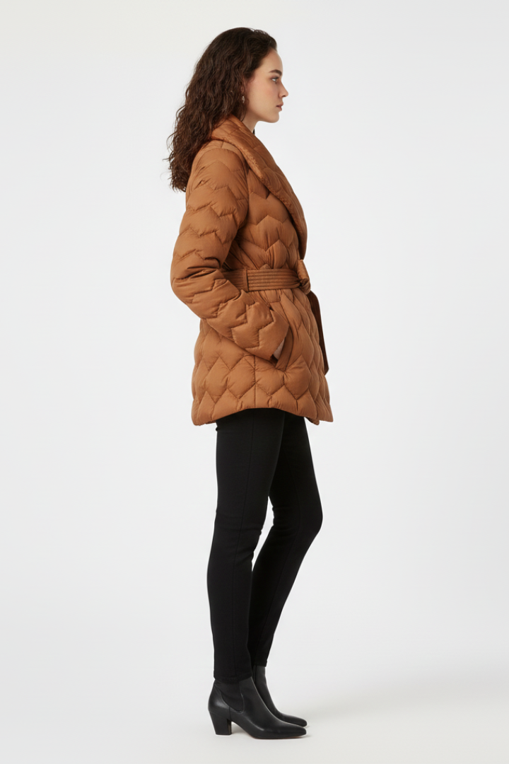 Women’s down coat by THE WHITMORE FAMILY in caramel color, featuring a belted waist and deep pockets for warmth and style.