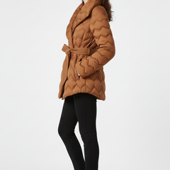 Women’s down coat by THE WHITMORE FAMILY in caramel, with belted waist and deep pockets, shown on a model.