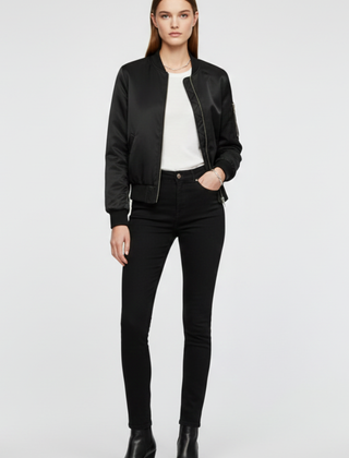Women’s black bomber jacket by THE WHITMORE FAMILY with zipper closure and ribbed accents, displayed on a model.