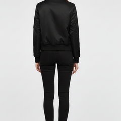 Women’s black bomber jacket by THE WHITMORE FAMILY featuring zipper closure and ribbed details, styled for a casual look.