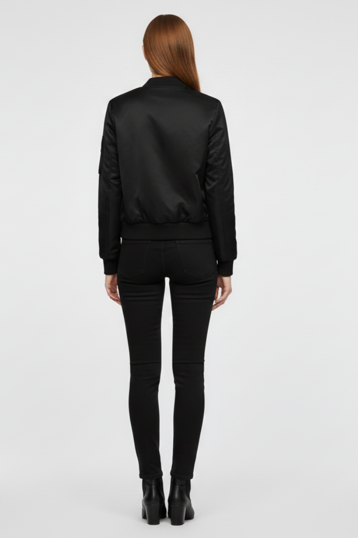Women’s black bomber jacket by THE WHITMORE FAMILY featuring zipper closure and ribbed details, styled for a casual look.