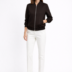 Black women's bomber jacket by THE WHITMORE FAMILY featuring zip closure and ribbed edges, displayed on a hanger.