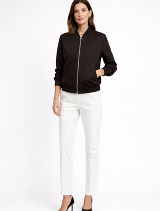 Black women's bomber jacket by THE WHITMORE FAMILY featuring zip closure and ribbed edges, displayed on a hanger.