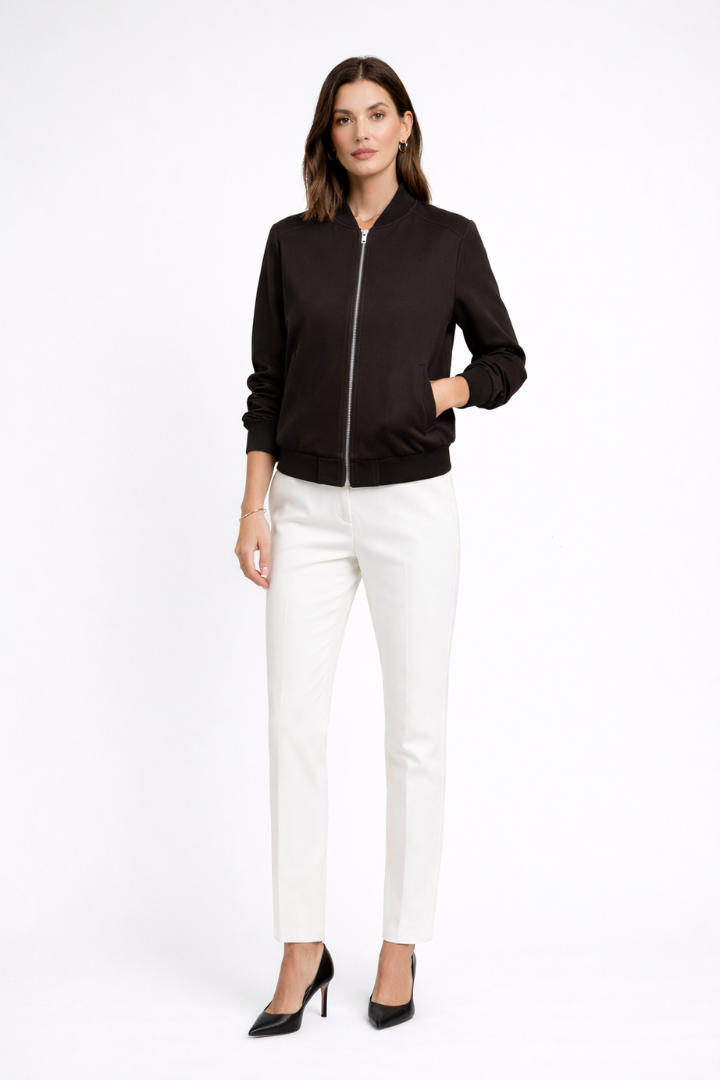 Black women's bomber jacket by THE WHITMORE FAMILY featuring zip closure and ribbed edges, displayed on a hanger.
