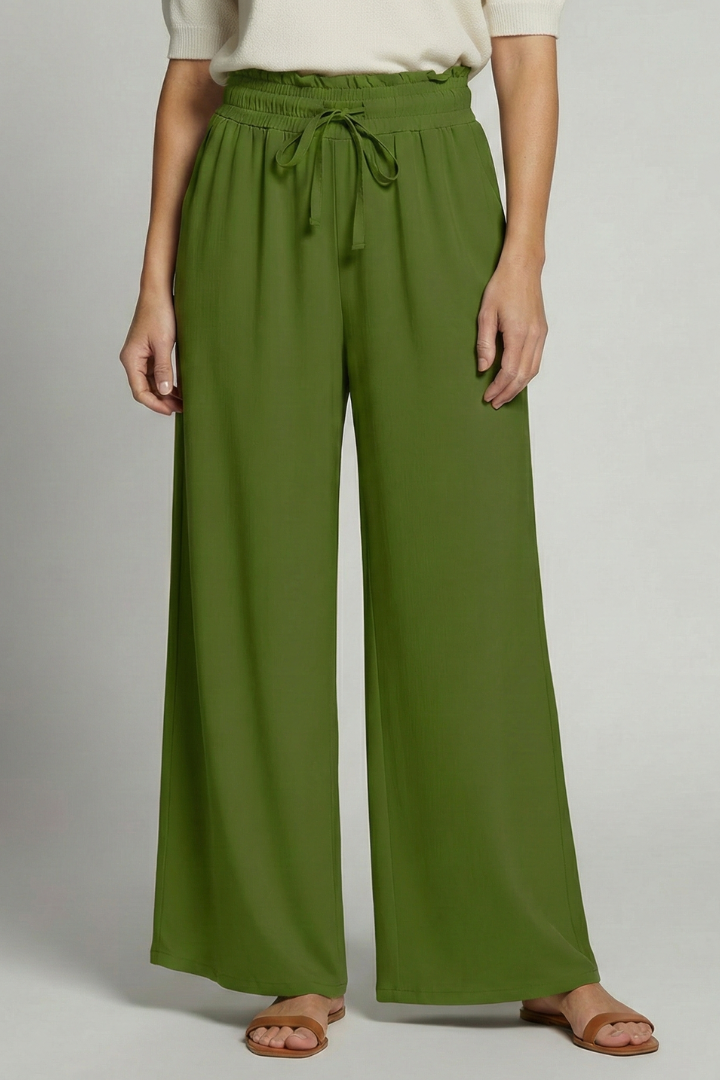 Women's Palazzo Trousers by THE WHITMORE FAMILY with elastic waist and side pockets, shown in a relaxed fit and flowy fabric.