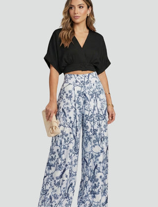 Women’s black two-piece set with V-neck top and wide-leg trousers from THE WHITMORE FAMILY, styled on a model.