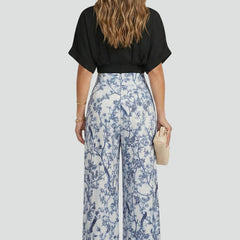 Women's two-piece set by THE WHITMORE FAMILY featuring a black V-neck top and wide-leg trousers, casual and stylish for everyday wear.